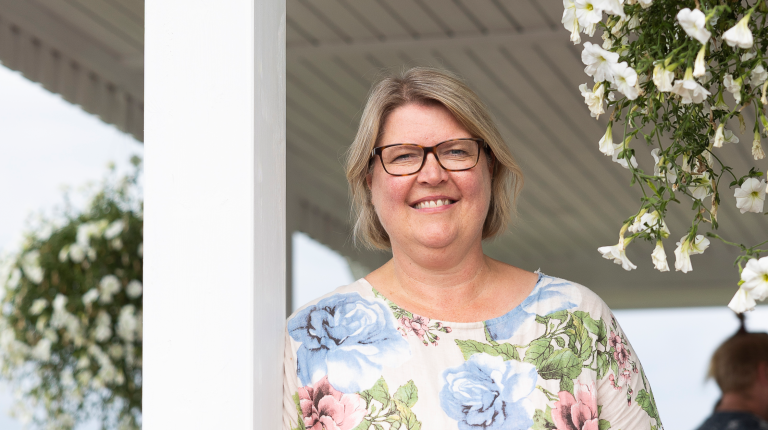 Omakotiliiton toiminnanjohtaja Marju Silander hymyilee pientalon kesäkukilla koristellulla terassilla